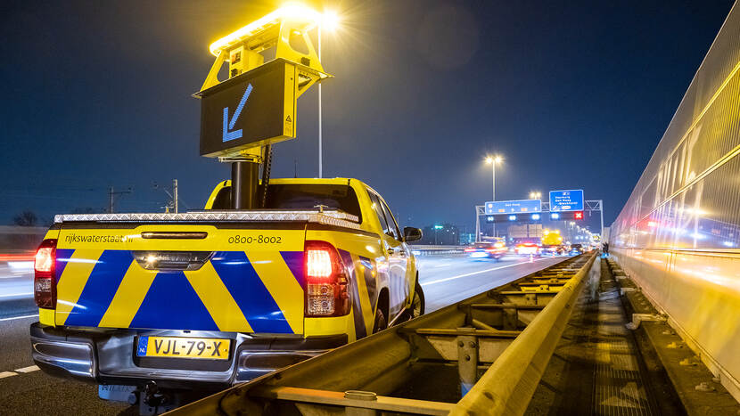 Foto van Rijkswaterstaat auto op de snelweg met bord dat richting aangeeft