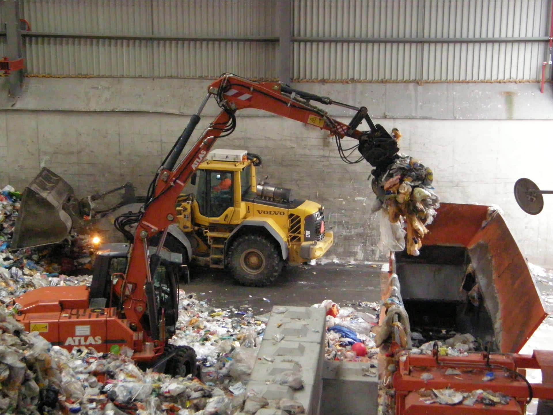Een shovel schuift afval aan de kant in een loods van een afvalverwerker