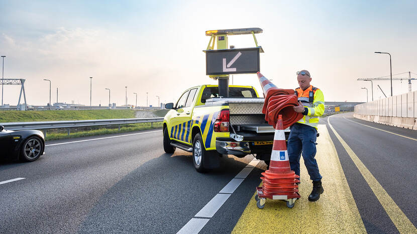 Medewerker Rijkswaterstaat verkeerskegels aan het binnenhalen op de snelweg